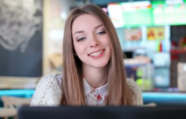 Красивая девушка улыбается перед экраном монитора