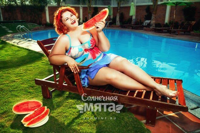 Полная женщина ест арбуз, лежа у бассейна, фото